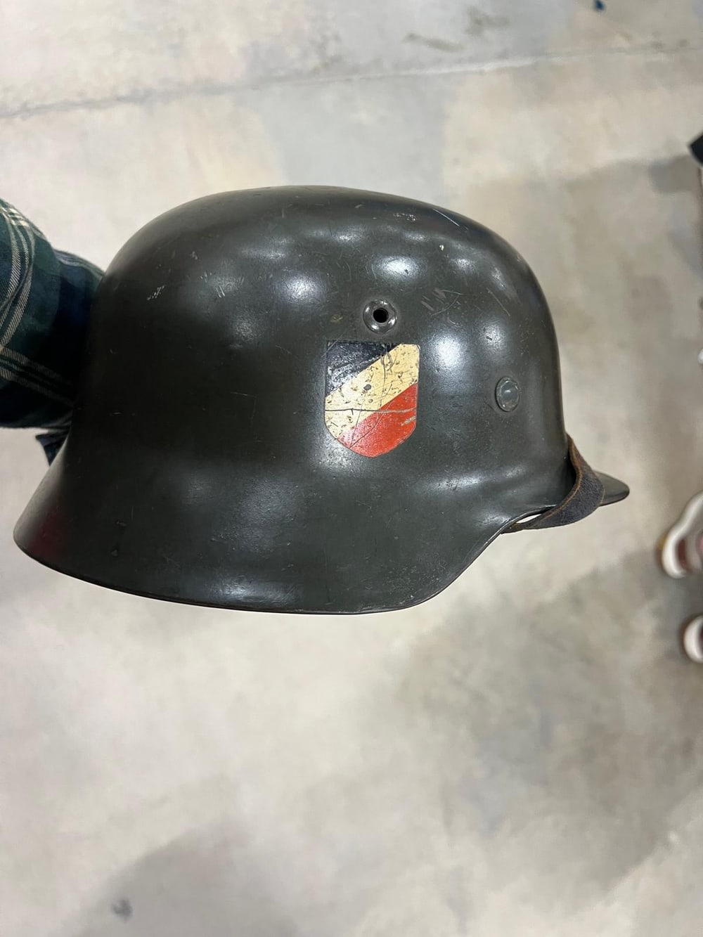 Deutscher Stahlhelm aus dem Zweiten Weltkrieg, komplett und mit beiden Abzeichen: auf dieser Seite das Wappenschild in Schwarz-Weiß-Rot.