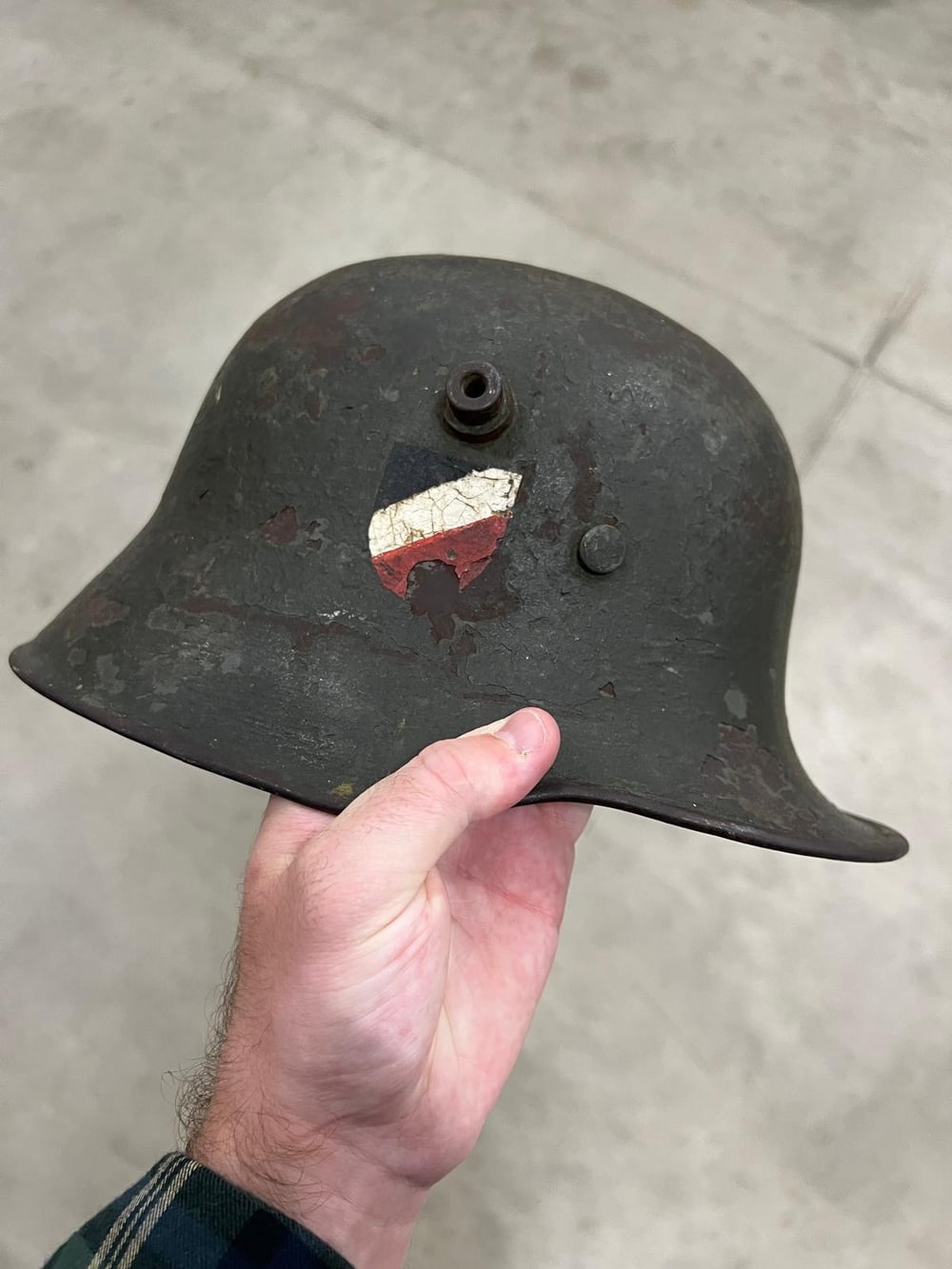Deutscher Stahlhelm aus dem Ersten Weltkrieg mit den seitlichen Lüftungsbolzen und aufgemaltem schwarz-weiß-rotem Schild, unrestauriert.
