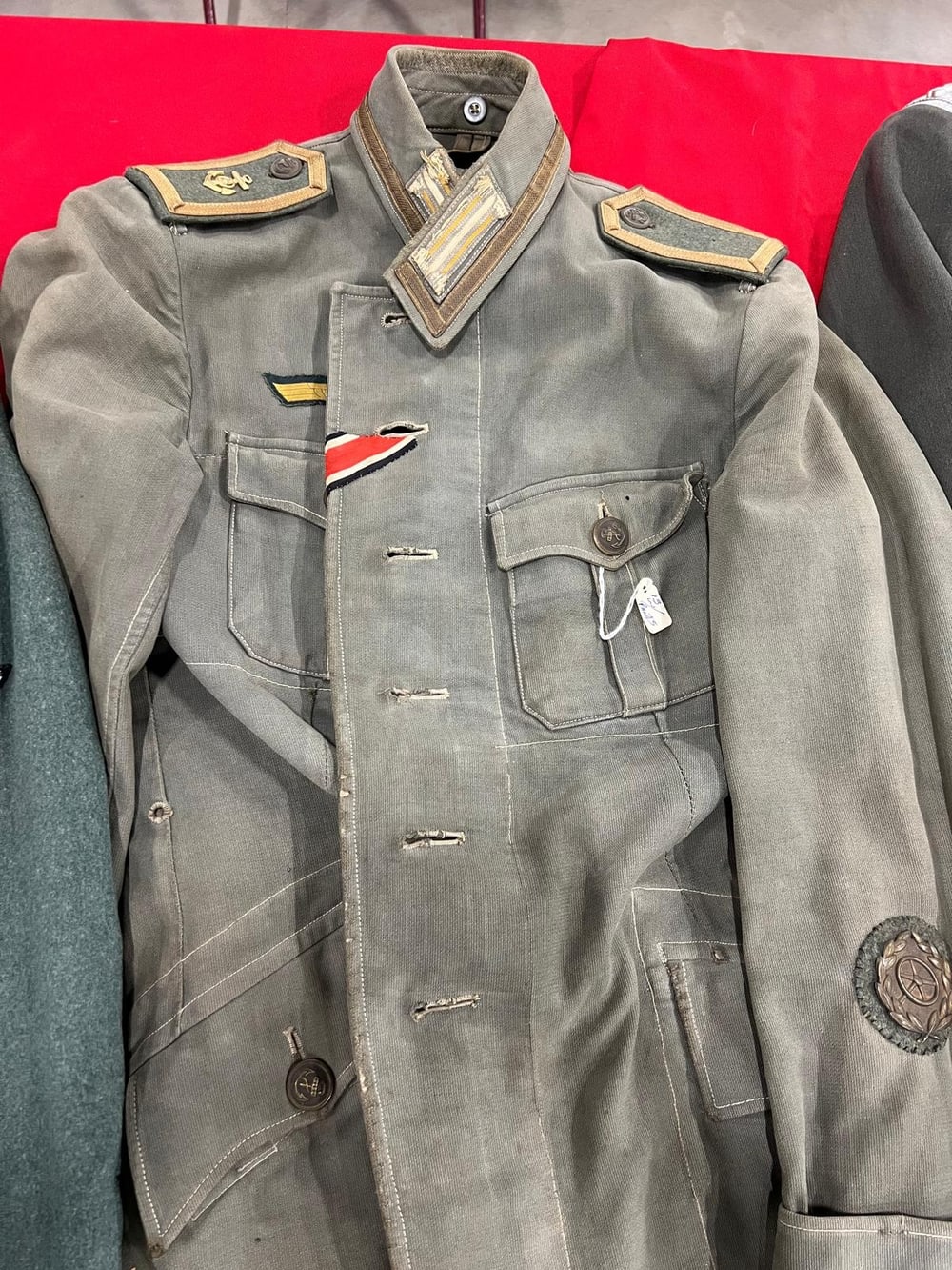Feldgraue Feldbluse der Kriegsmarine: Schulterklappen mit Anker, Band des Eisernen Kreuzes im Knopfloch und Kraftfahrerabzeichen am Ärmel.
